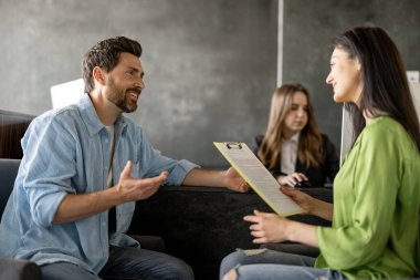 Kadın ve erkek modern kliniğin resepsiyonunda bazı belgeler imzalıyor. Genç aile, doktoru ziyaret etmeden önce hastaneyi ziyaret ediyor.
