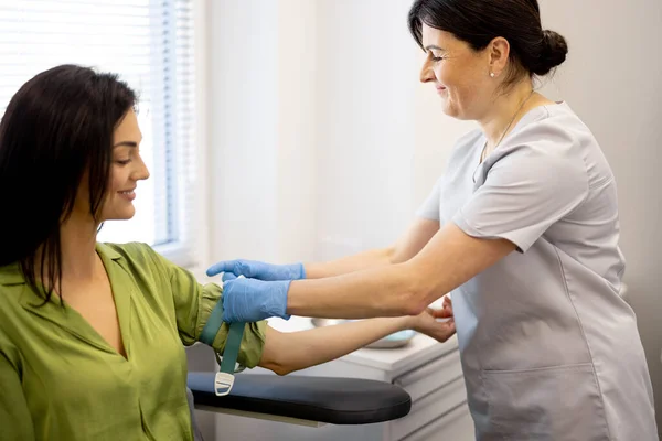 간호원은 실험실에 여자의 팔에서 검사를 받는다 의사들 은피를 취하기 지혈대로 — 스톡 사진
