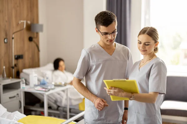 Två Unga Sjuksköterskor Samtalar När Står Tillsammans Sjukavdelningen Med Patienter — Stockfoto