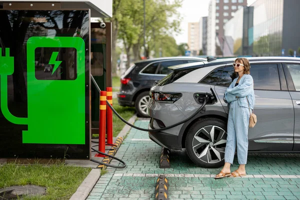 年轻女子在城市的一个公共收费站等着她的电动车被收费 现代生活方式和绿色交通运输概念 — 图库照片