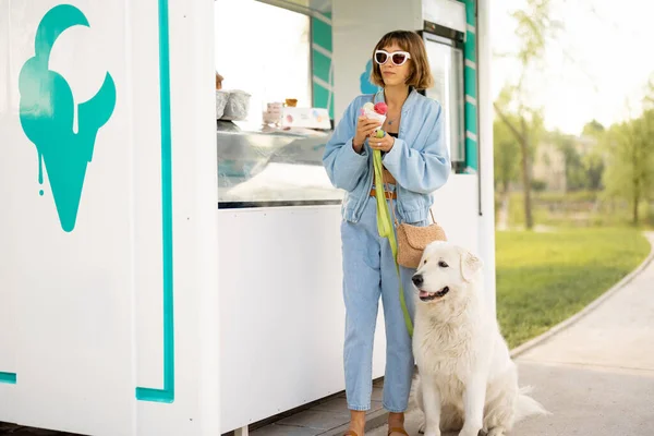 公園で犬と一緒に歩いている間 美しい店で買うためにアイスクリームを選ぶ若い女性 屋外でペットと一緒に夏の時間を過ごす — ストック写真