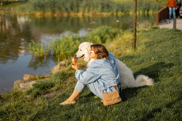 Młoda Kobieta Lody Siedząc Swoim Słodkim Białym Psem Pobliżu Jeziora — Zdjęcie stockowe