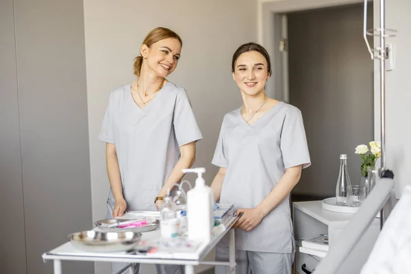两个年轻快乐的护士在医务室吃药的画像 护理和医疗支助概念 — 图库照片