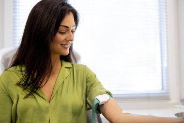 Cheerful woman waiting for blood tests to be taken while sitting in the laboratory