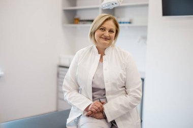 Ofiste orta yaşlı bir hemşirenin portresi. Klinikte sarı saçlı, beyaz, güzel bir sağlık görevlisi.