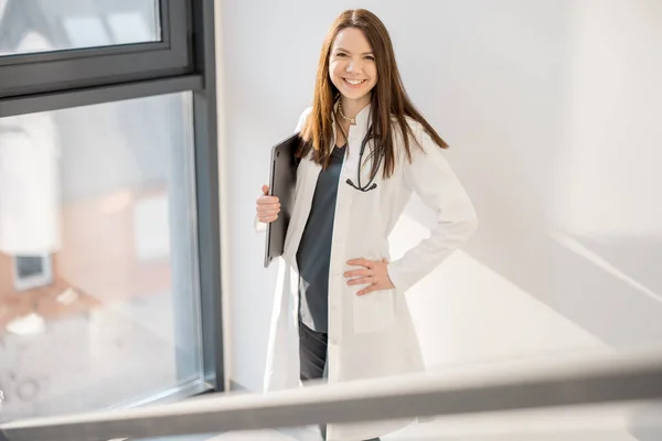 现代门诊部一位身穿医袍 头戴文件夹的女医生的画像 — 图库照片