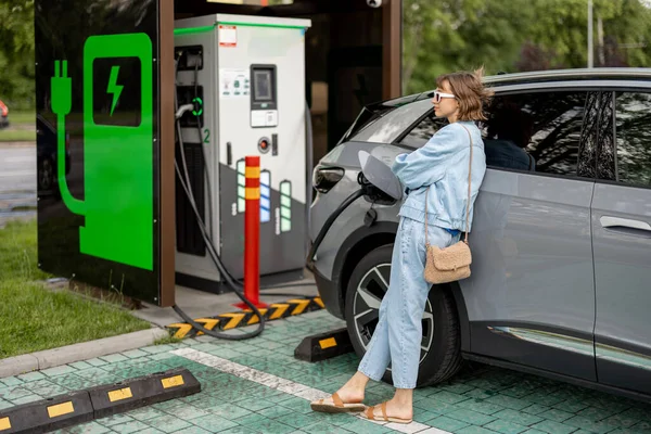 年轻女子在城市的一个公共收费站等着她的电动车被收费 现代生活方式和绿色交通运输概念 — 图库照片