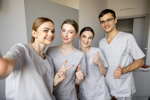 stock image Young team of nurses making selfie photo, while standing together in medical ward. Portrait of cheerful nurses in clinic