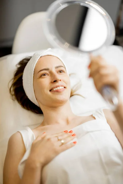 Šťastná Žena Dívá Zrcadla Své Tváři Kosmetických Procedur Zatímco Leží — Stock fotografie