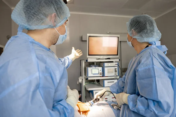 两名外科医生用内窥镜进行微创手术 在手术室观察监视器 内窥镜电脑辅助治疗的概念 — 图库照片