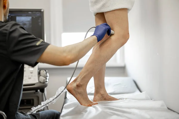 Ultrasound specialist is scanning the veins on a womans leg, examining veins for varicose treatment