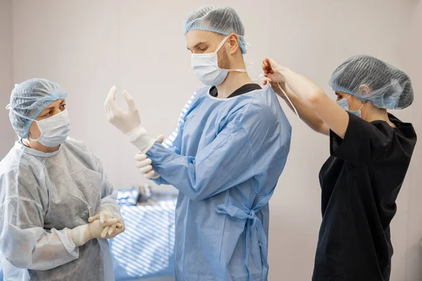 Медсестра Хирургом Готовится Операции Носит Стерильную Униформу Операционной Пациентом Лежащим — стоковое фото