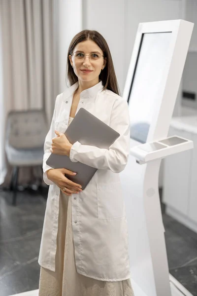 Portrait of a doctor standing near body analyzer machine at beauty salon. Concept of non-invasive and quick body research for beauty industry