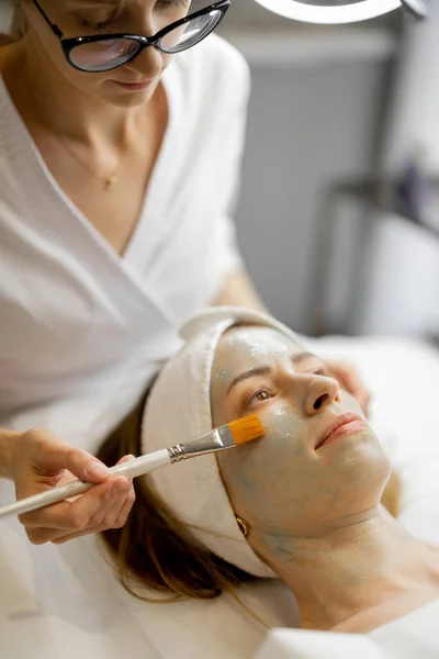 Kosmetikerin Trägt Schönheitssalon Schönheitsmaske Mit Einem Pinsel Auf Das Gesicht — Stockfoto