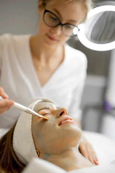 Cosmetologist Påfører Skjønnhetsmaske Med Børste Kvinnelig Ansikt Skjønnhetssalongen Ansiktspleie Konsept – stockfoto
