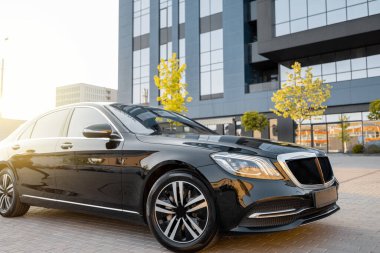 Bir ofis binasının yakınındaki caddede lüks siyah bir araba. İş devir hizmeti kavramı ve ulaşım kavramı