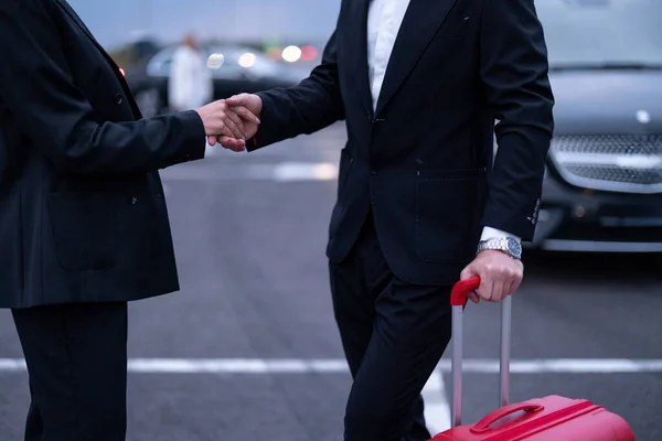 駐車場のスーツケースと一緒に立っている間 ビジネスカップルは互いに握手します 出張のコンセプト — ストック写真