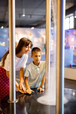 Anne ve küçük bir çocuk fiziği bir bilim müzesini ziyaret ederken fiziksel fenomenleri gösteren bir model üzerinde interaktif olarak öğreniyorlar. Çocuk eğlencesi ve öğrenme kavramı