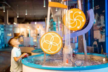 Küçük çocuk toplarla oynar, fiziksel fenomenleri ilginç bir şekilde öğrenir, interaktif modellerle bilim müzesinde eğlenir.