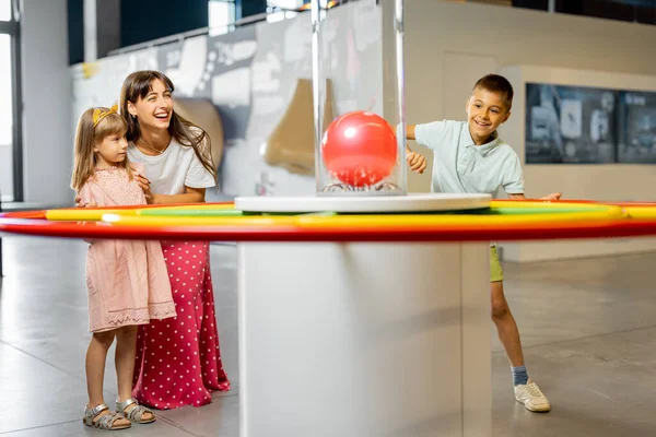 子供と一緒にいる母親は 科学博物館を訪問しながら物理現象を示すモデルに物理学を相互に学びます 児童エンターテインメントと学習の概念 — ストック写真