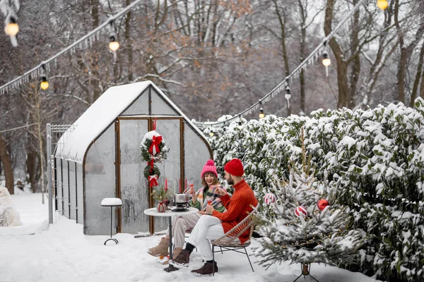 男人和女人一起吃着浪漫的晚餐 同时坐在装饰精美的雪地后院里的餐桌旁 庆祝寒假的年轻家庭 — 图库照片