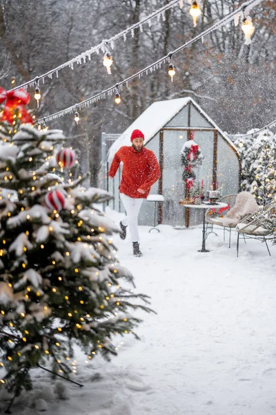 可爱的男人在装饰精美的雪地后院里欢欢喜喜地跳着过冬 前面是圣诞树 冬天的娱乐和闲暇时间的概念 — 图库照片