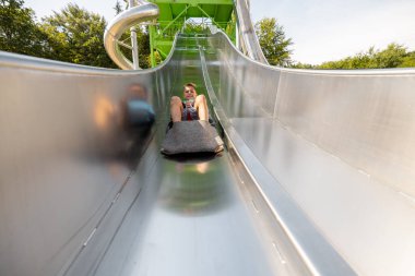 Çocuklar eğlence parkına gelip eğlenmek için kayarak kayıyorlar. Yaz tatili ve çocuk eğlencesi kavramı