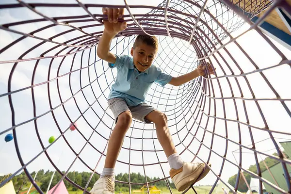 少年は遊園地で遊んでいる間 網を登ります エンターテイメントと夏休みのコンセプト — ストック写真