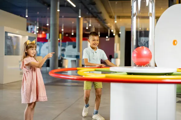 Little boy and girl learn physics interactively on a model that shows physical phenomena while visiting a science museum. Concept of childrens entertainment and learning