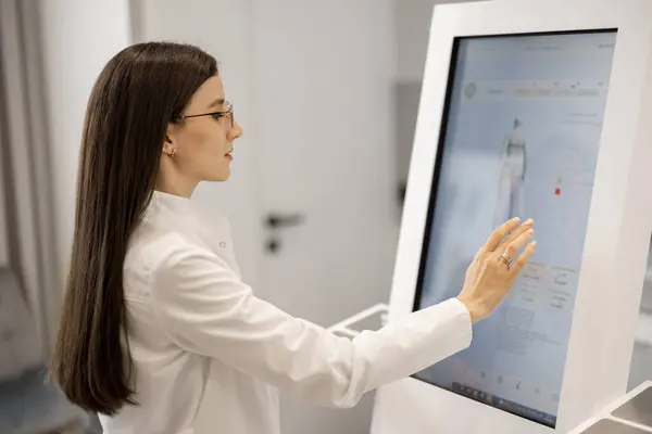 Portrait of a doctor touching the screen of body analyzer machine at beauty salon. Concept of modern technologies in medicine and beauty industry