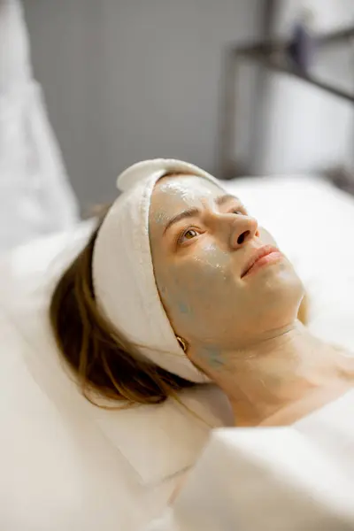 Woman with a beauty mask on her face lying during beauty procedure in salon