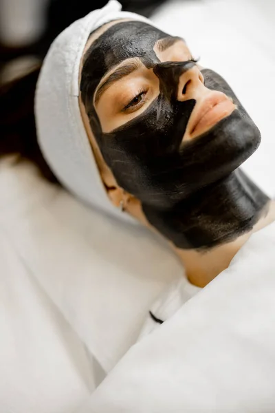 Young womans face in carbon mask ready for laser carbon peeling at beauty salon, close-up. Concept of beauty and facial care