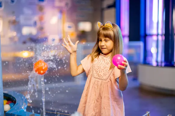 小さな女の子は水の蒸気にボールで遊び 興味深い方法で物理現象を学び インタラクティブなモデルを持つ科学博物館で楽しんでいます — ストック写真