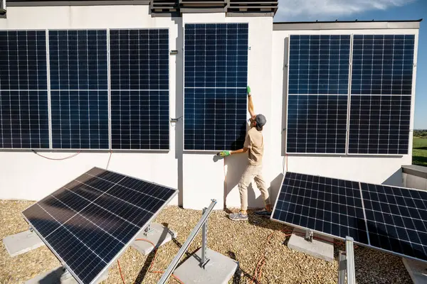 Mies Asentamassa Aurinkopaneeleita Pystysuoralle Seinälle Talonsa Katolle Omaan Kulutukseen Uusiutuvan — kuvapankkivalokuva