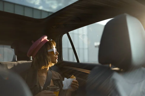 Nuori Tyylikäs Nainen Istuu Kahvikupin Croissantin Kanssa Modernin Taksin Takapenkillä — kuvapankkivalokuva