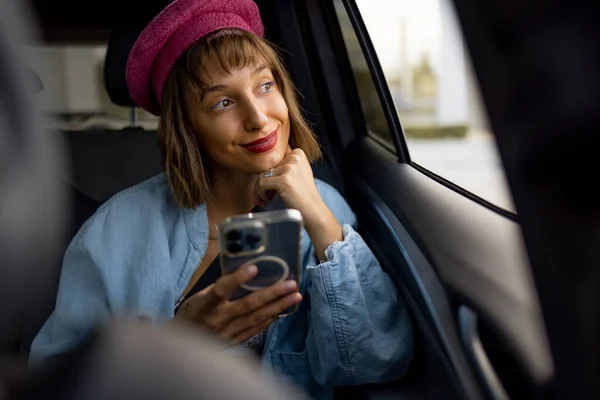 Junge Stilvolle Frau Nutzt Smartphone Und Schaut Aus Dem Fenster — Stockfoto