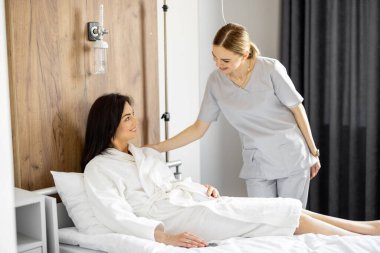 Hemşire, rehabilitasyon sırasında ya da koğuşta tedavi görürken kadın hastayla sohbet ediyor. Tedavi sırasında tıbbi ve psikolojik destek kavramı