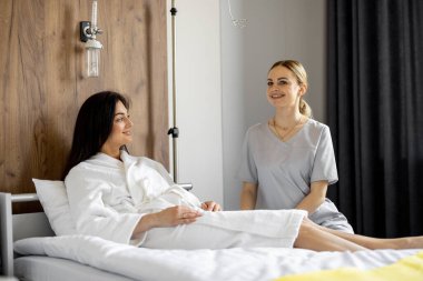 Hemşire, rehabilitasyon sırasında ya da koğuşta tedavi görürken kadın hastayla sohbet ediyor. Tedavi sırasında tıbbi ve psikolojik destek kavramı