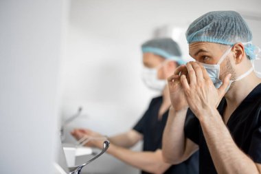 Cerrahlar ameliyat için maske takıp ellerini yıkıyorlar. Kısırlık ve ameliyat kavramı