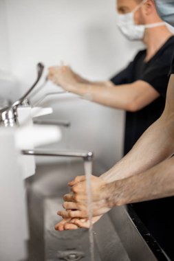 İki cerrah cerrahi bir ameliyata hazırlanırken ellerini dikkatlice yıkadı. Kısırlık ve ameliyat kavramı