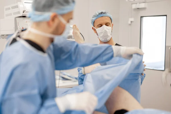 Preparation for surgical operation. Surgeons covers the patient with a sterile drape
