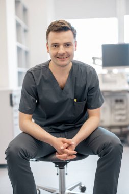 Klinikteki iş yerinde oturan ultrason teşhisinde uzman bir yetişkinin portresi. Ultrason muayenesi ve tanı konsepti