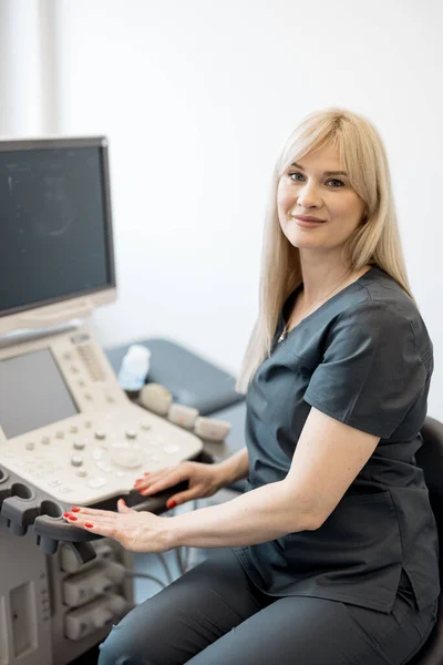 Portrait of adult medical specialist in ultrasound diagnostics sitting at her workplace in the clinic. Concept of ultrasound examination and diagnostics