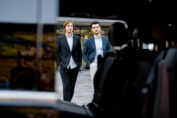Dwóch Biznesmenów Wchodzi Samochodu Budynku Widokiem Przez Drzwi Samochodu Pojęcie — Zdjęcie stockowe