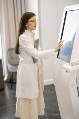 Güzellik salonundaki vücut analiz makinesine dokunan bir doktorun portresi. Güzellik endüstrisi için hızlı ve zararsız vücut araştırmaları kavramı