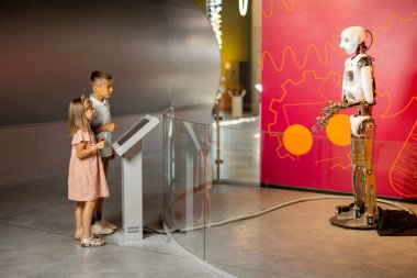Küçük oğlan ve kız bilim müzesini ziyaret eden bir robotla etkileşime geçecekleri için heyecanlılar. Modern teknoloji ve çocuk eğitimi kavramı