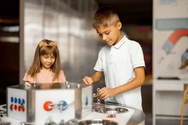 Kids play with magnets while studying physics in the science museum. Concept of childrens entertainment and learning