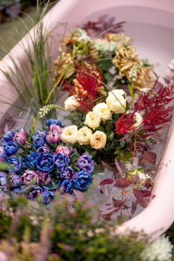 Pembe küvette suyla birlikte renkli kesilmiş çiçekler. Bir sürü çiçek, çiçek terapisi ve güzellik konsepti