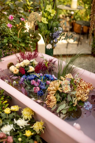 Colorful cut flowers in pink bathtub with water. Lots of blooming flowers, flower therapy and beauty concept
