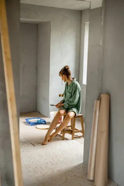 여자는 새로운 아파트의 수리를하는 페인트 의자에 앉아서 페인트 색상을 개념의 스톡 이미지